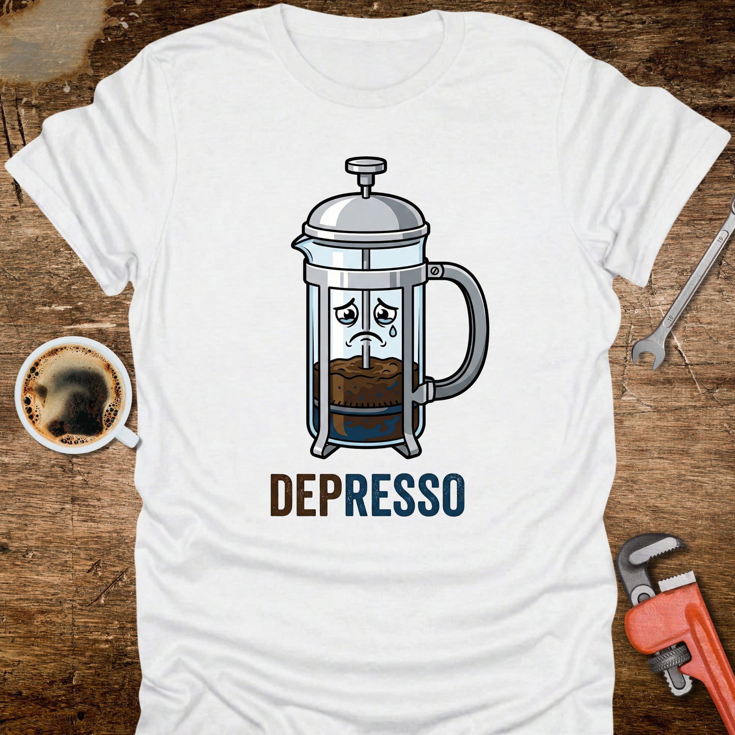White t-shirt with a coffee-themed graphic and 'DEPRESSO' text on a wooden surface with a coffee cup and tools.