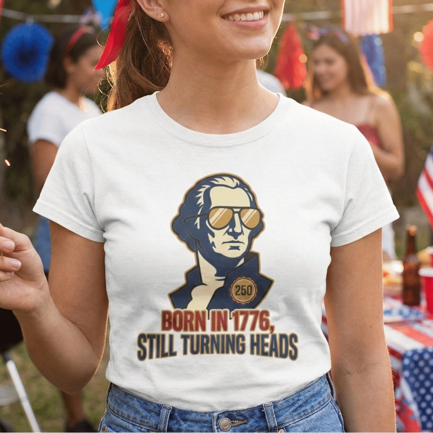 Woman wearing a t-shirt with a graphic of a person and text, standing outdoors with blurred people and flags in the background.