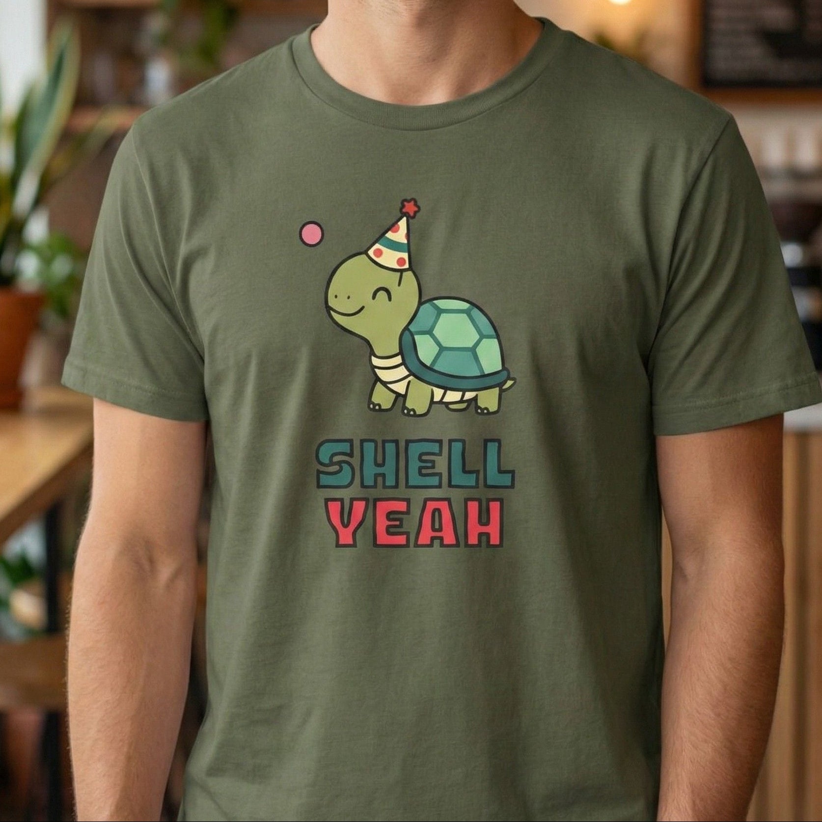 Person wearing a green t-shirt with a turtle graphic and 'Shell Yeah' text in a casual setting.
