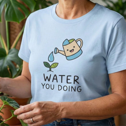 Woman wearing a light blue t-shirt with a graphic and text, standing in a room with plants.