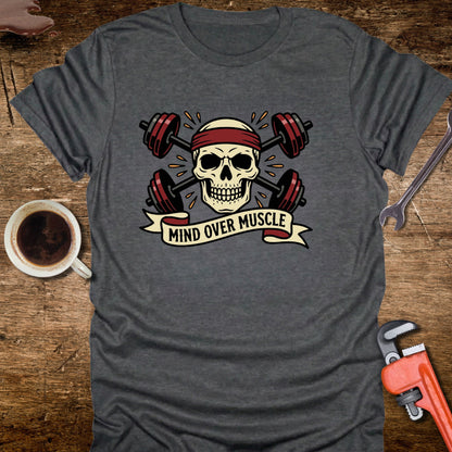 Gray t-shirt with skull and barbell design on a wooden surface with coffee and tools.