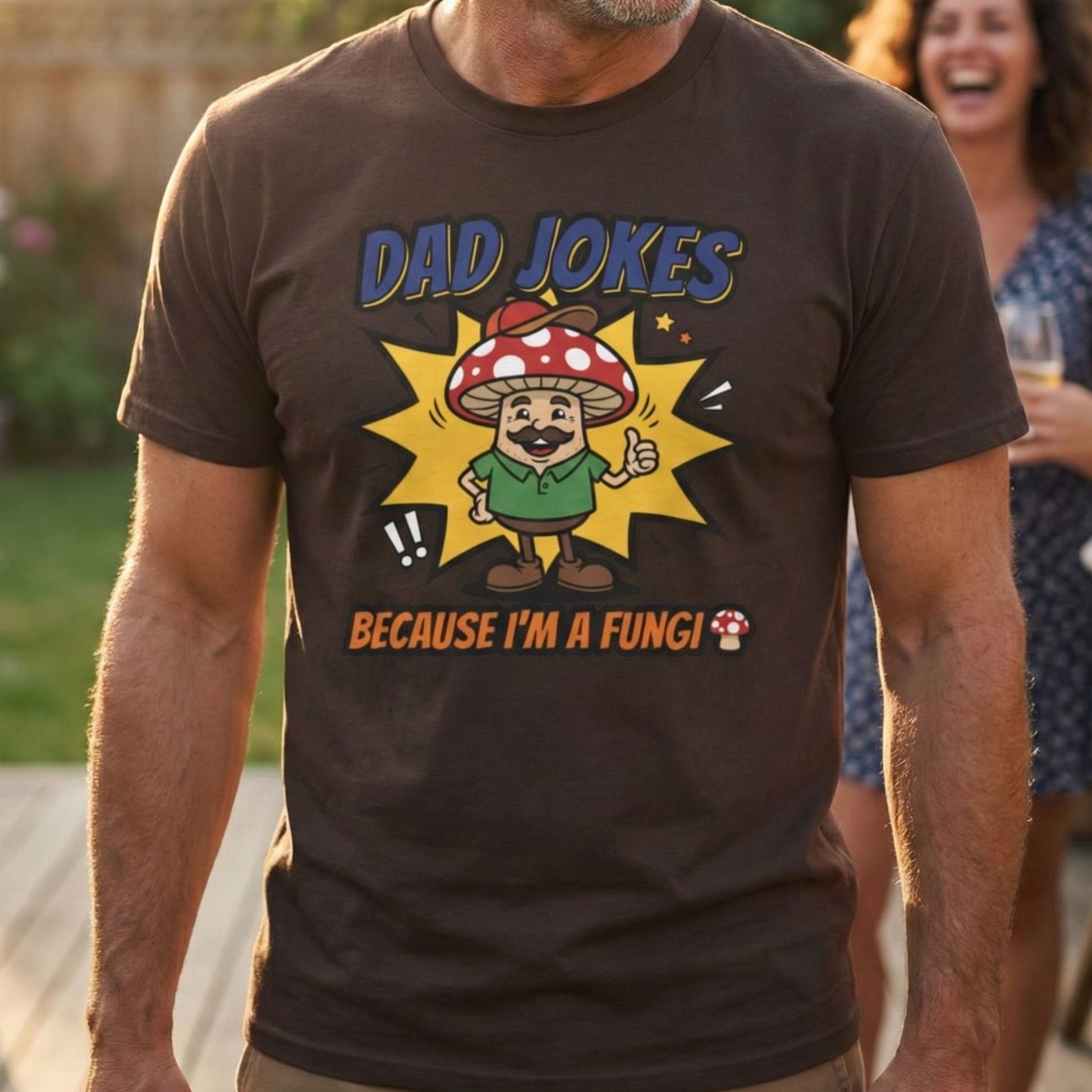 Man wearing a brown t-shirt with a cartoon mushroom character and text 'Dad Jokes Because I'm a Fungi' outdoors.