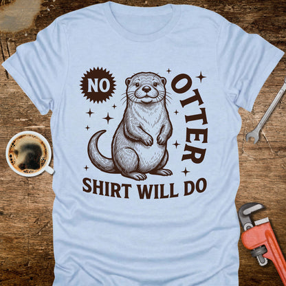 Light blue t-shirt with an otter graphic and text on a wooden surface with coffee and tools.