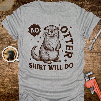 Gray t-shirt with an otter graphic and text on a wooden surface with coffee and tools.