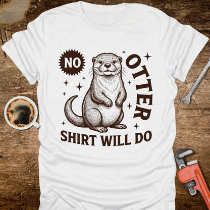 White t-shirt with an otter graphic and text on a wooden surface with coffee and tools.