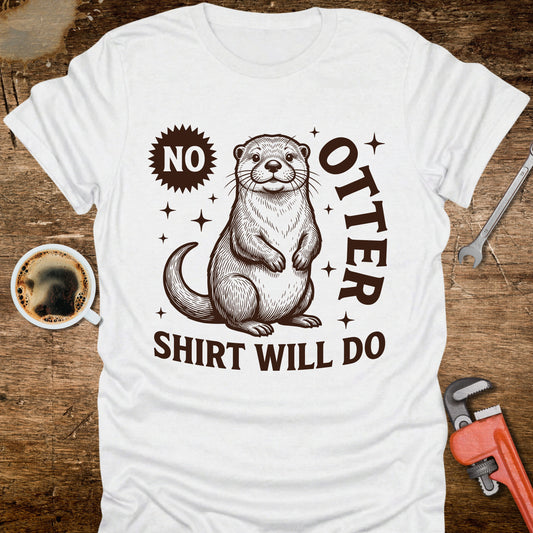 White t-shirt with an otter graphic and text on a wooden surface with coffee and tools.