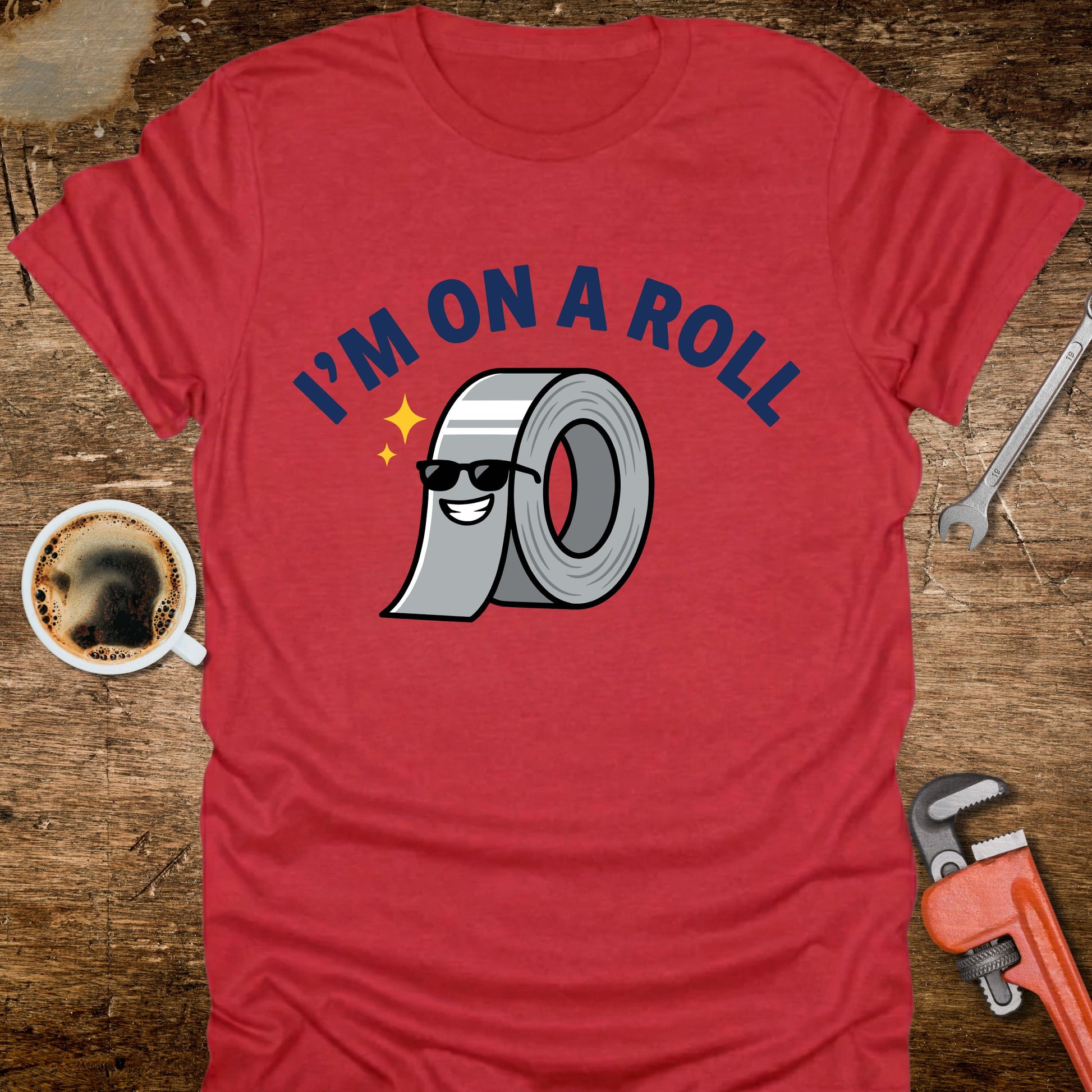 Red t-shirt with 'I'm on a Roll' graphic design on a wooden surface with coffee and tools.