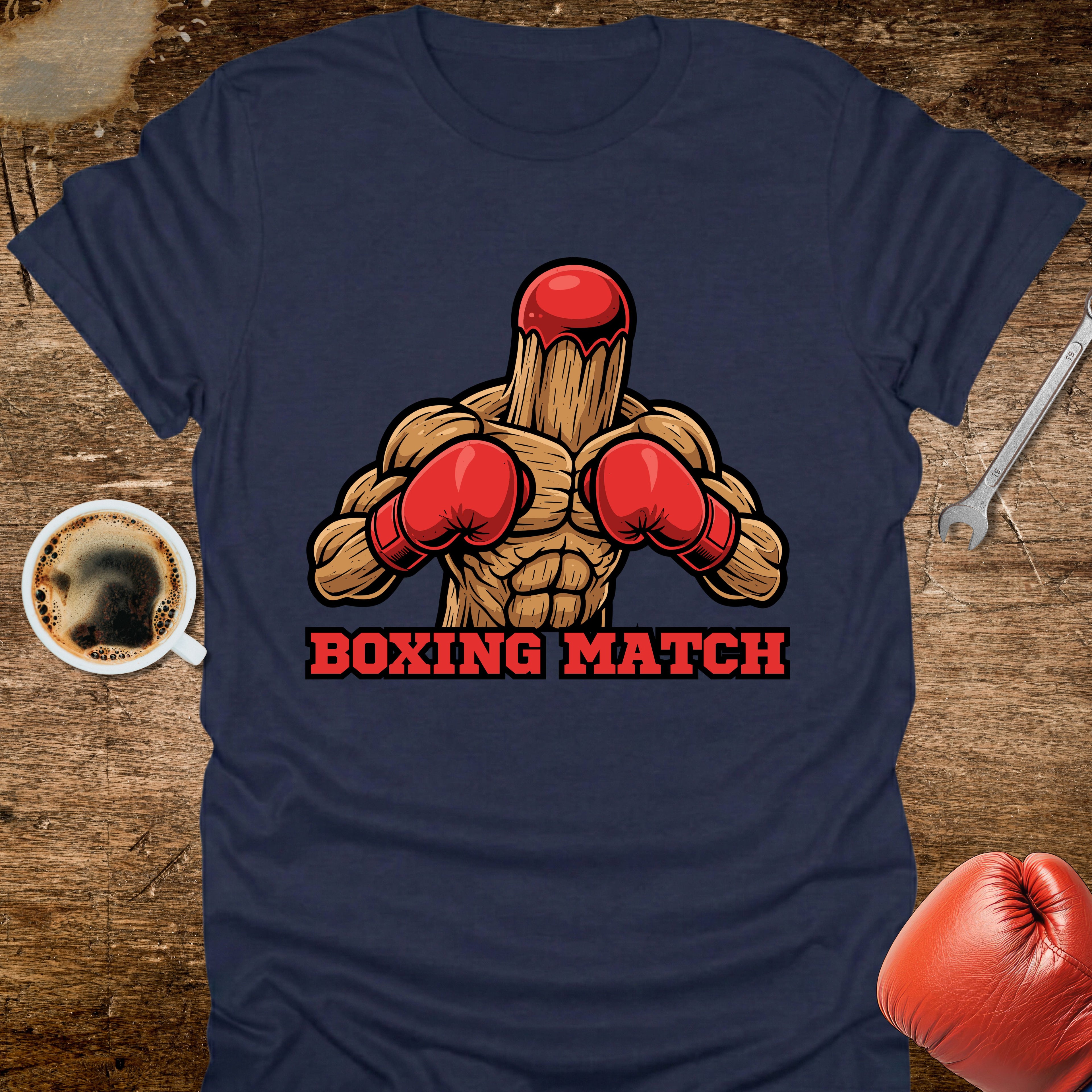 Navy blue t-shirt with a boxing graphic and 'Boxing Match' text on a wooden surface with coffee and boxing gloves.