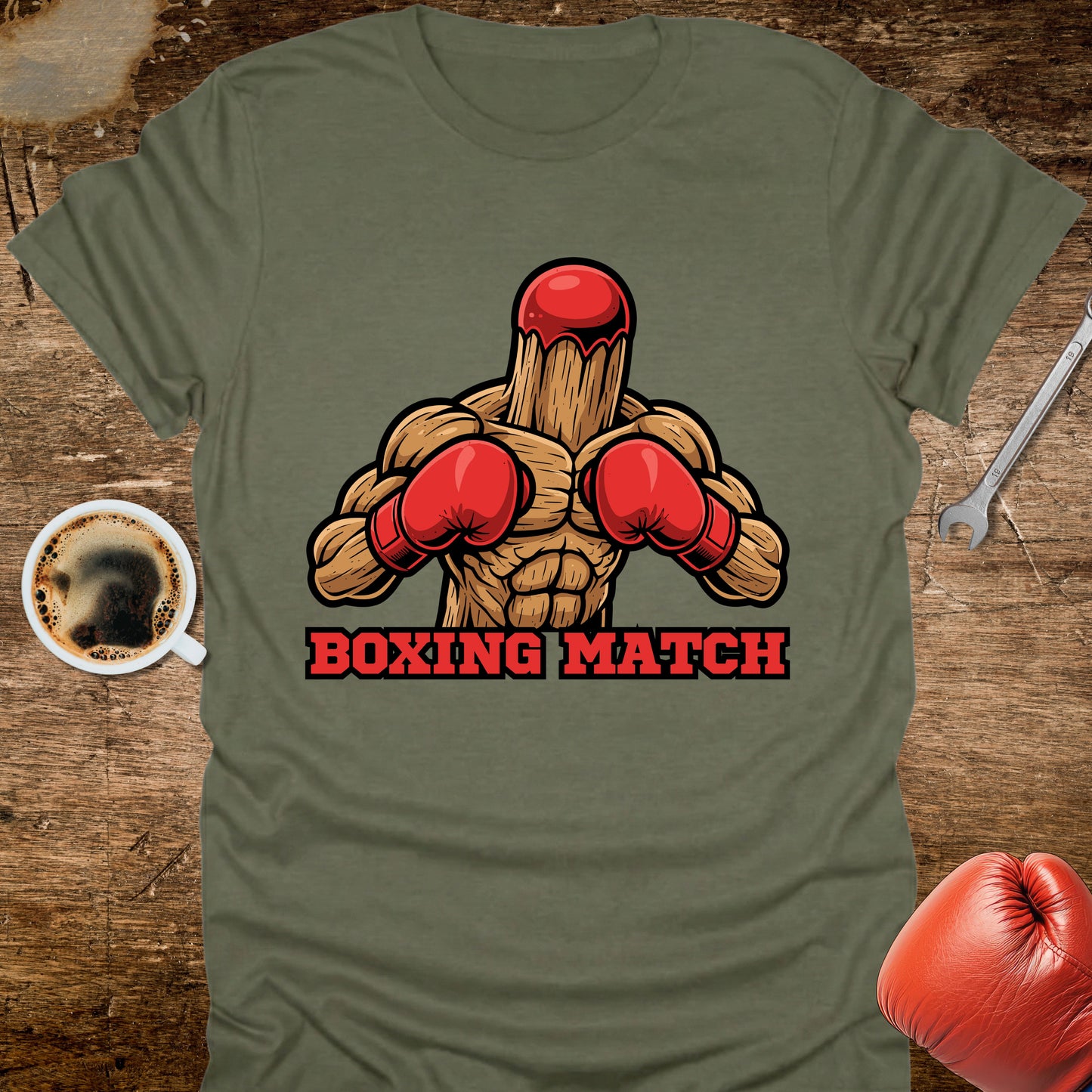 Green t-shirt with a graphic of a wooden figure in red boxing gloves and 'Boxing Match' text on a wooden surface.