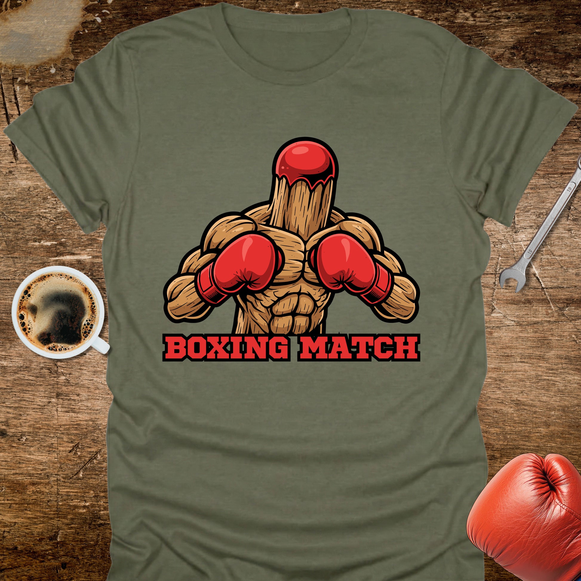 Green t-shirt with a graphic of a wooden figure in red boxing gloves and 'Boxing Match' text on a wooden surface.
