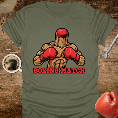 Green t-shirt with a graphic of a wooden figure in red boxing gloves and 'Boxing Match' text on a wooden surface.