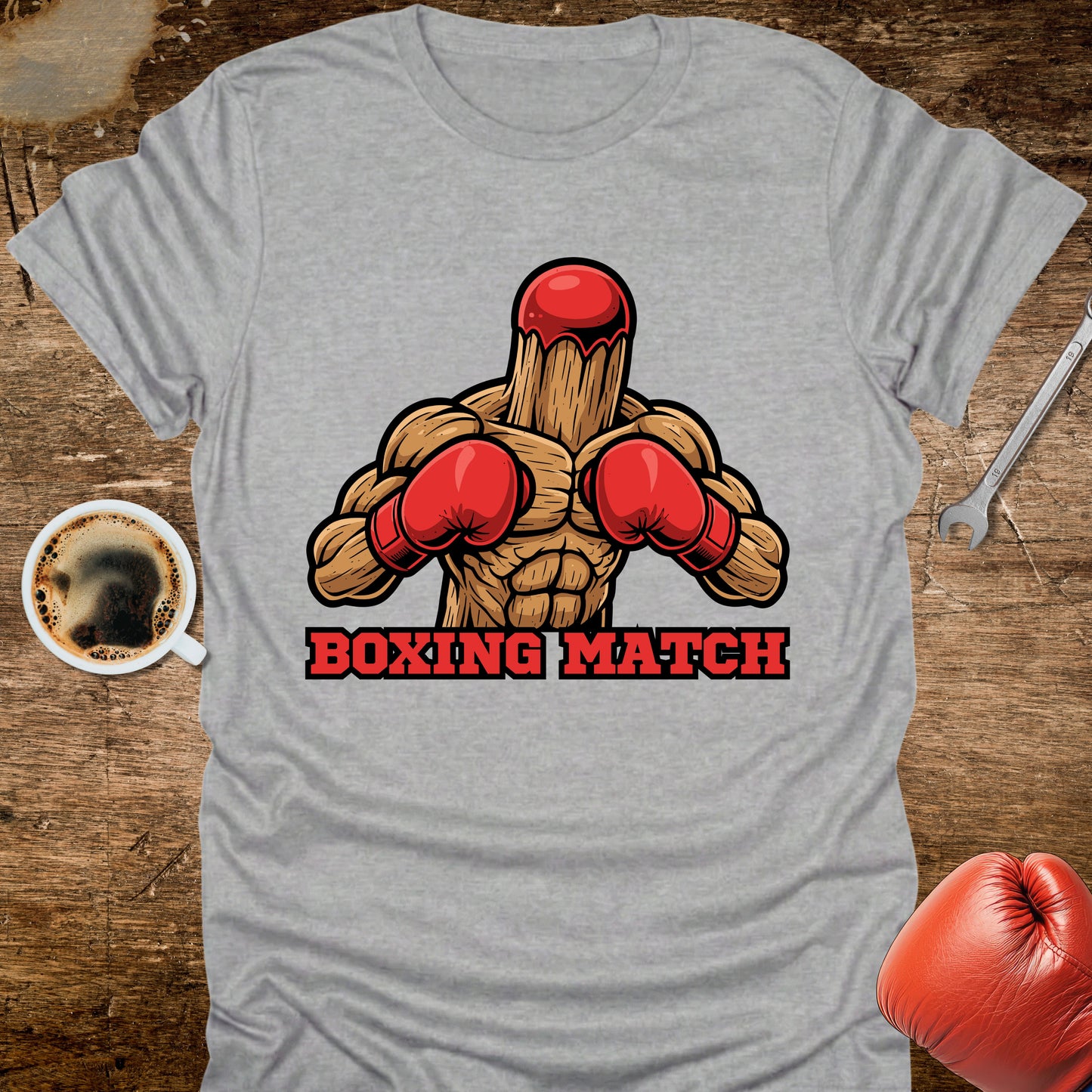 Gray t-shirt with a graphic of a wooden stick figure in boxing gloves and 'Boxing Match' text on a wooden surface.