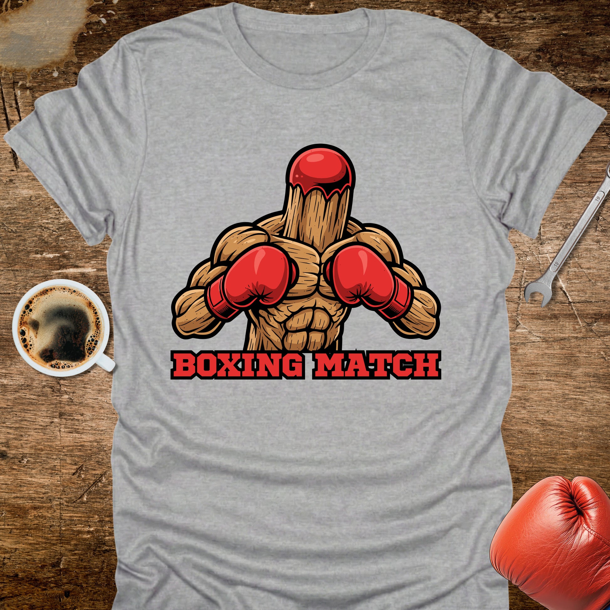 Gray t-shirt with a graphic of a wooden stick figure in boxing gloves and 'Boxing Match' text on a wooden surface.
