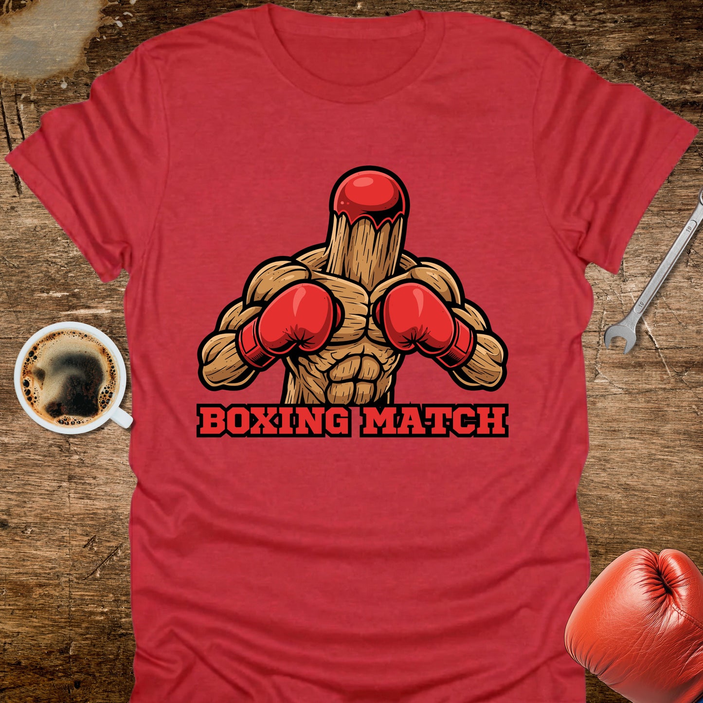 Red t-shirt with boxing graphic and 'Boxing Match' text on a wooden surface with coffee and gloves.