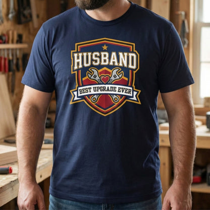 Person wearing a navy blue t-shirt with 'Husband Best Upgrade Ever' graphic design in a workshop.