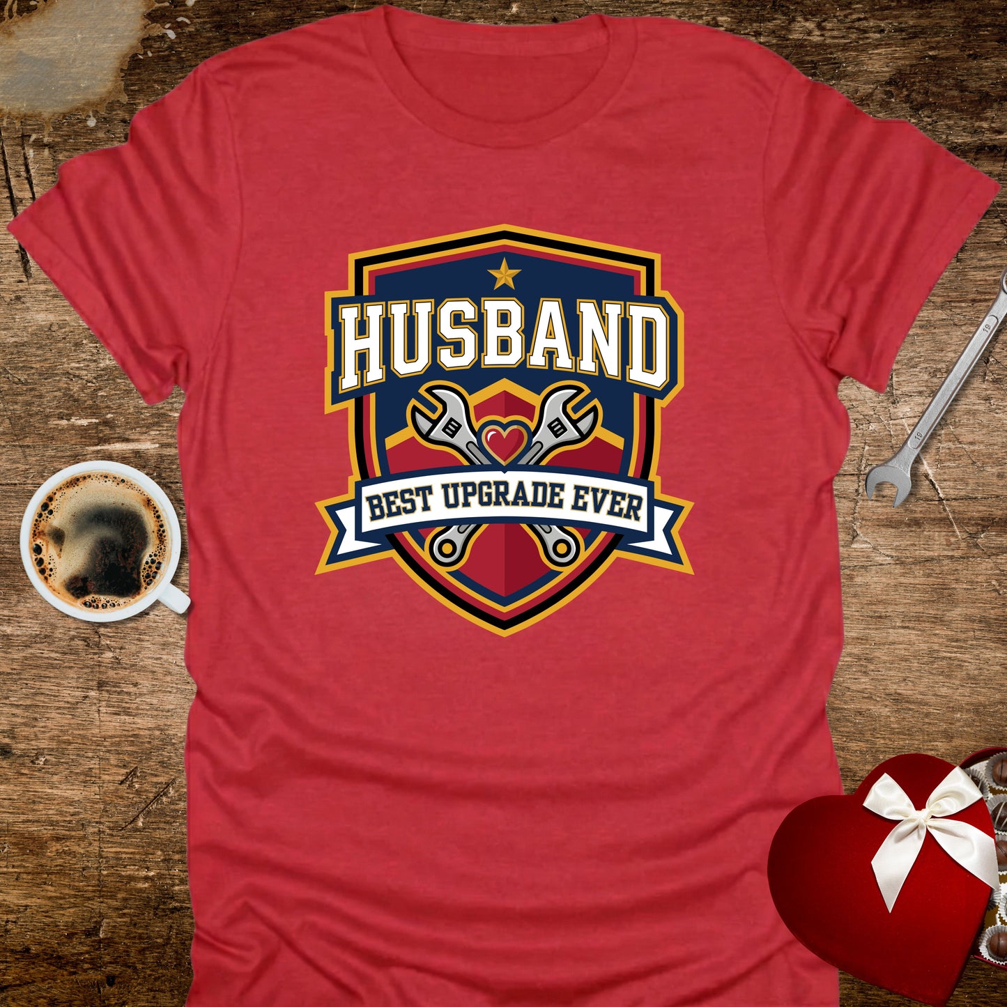 Red t-shirt with 'Husband Best Upgrade Ever' graphic on a wooden surface with coffee and tools.