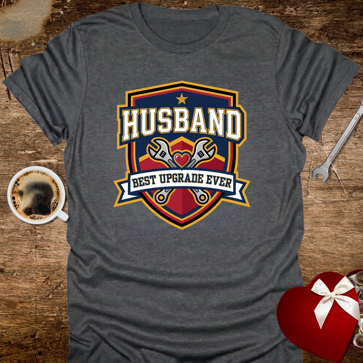 Gray t-shirt with 'Husband Best Upgrade Ever' graphic on a wooden surface with coffee and gift.