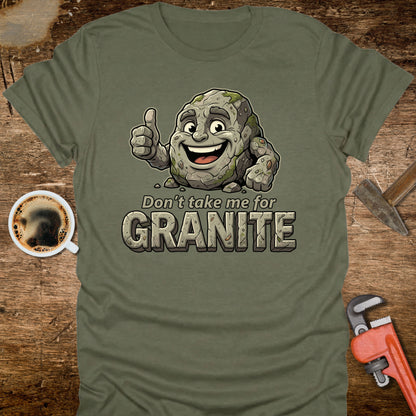 Green t-shirt with cartoon granite character and text 'Don't take me for Granite' on a wooden surface with coffee and wrench.