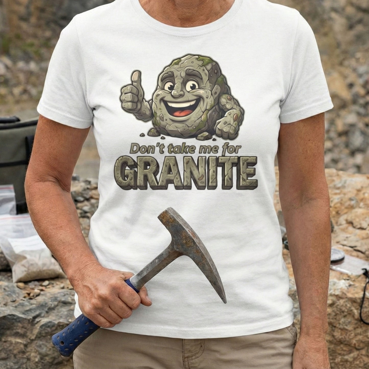 Person wearing a t-shirt with a cartoon character and text 'Don't take me for Granite' holding a hammer outdoors.