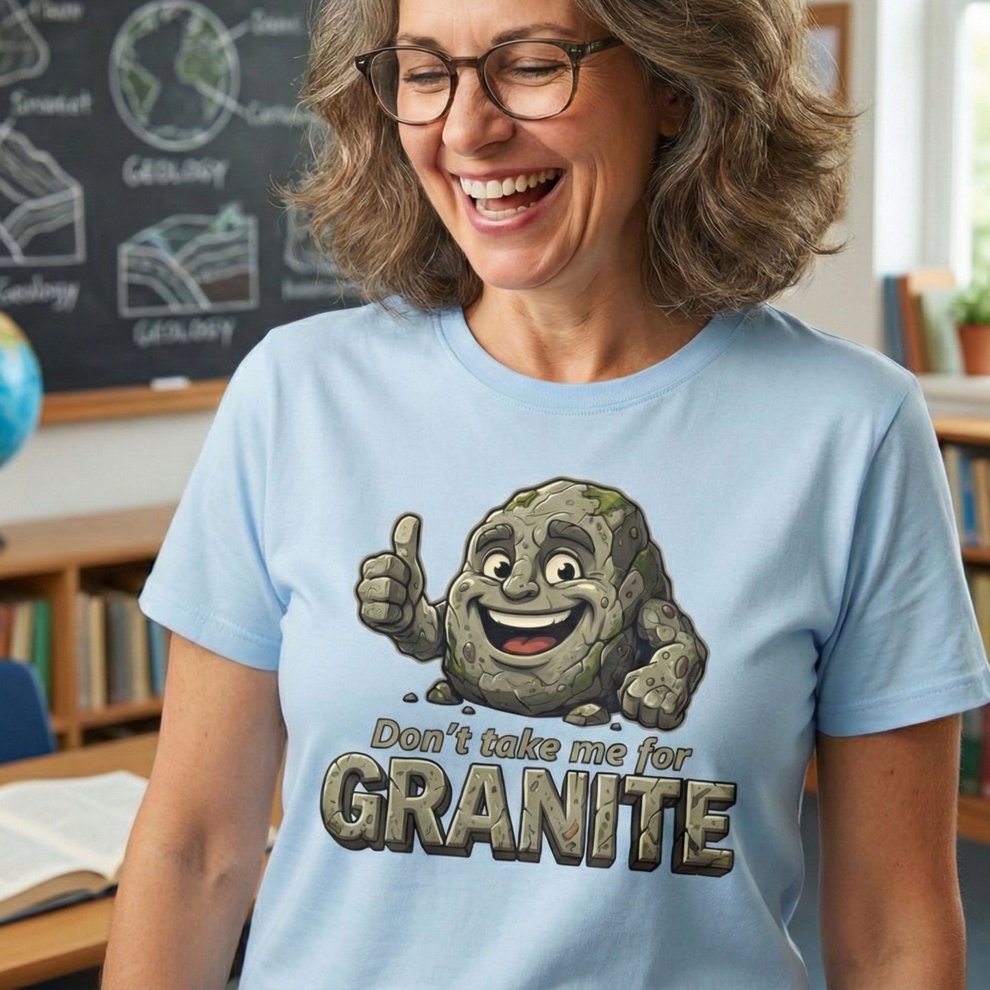 Woman wearing a light blue t-shirt with a cartoon rock character and text in a classroom setting