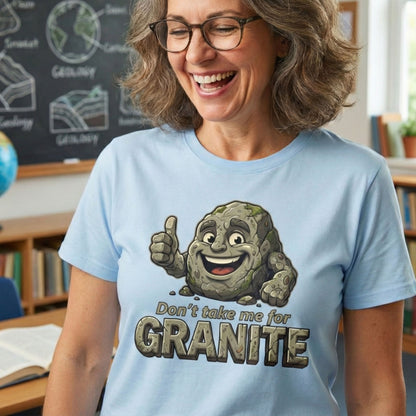 Woman wearing a light blue t-shirt with a cartoon rock character and text in a classroom setting