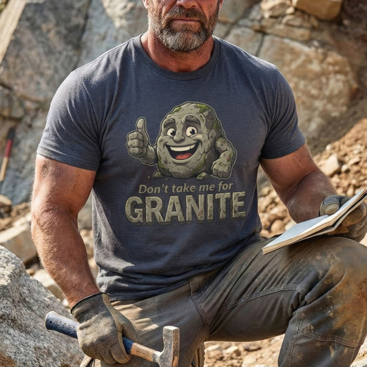 Man wearing a t-shirt with a cartoon rock character and text, sitting on rocks.