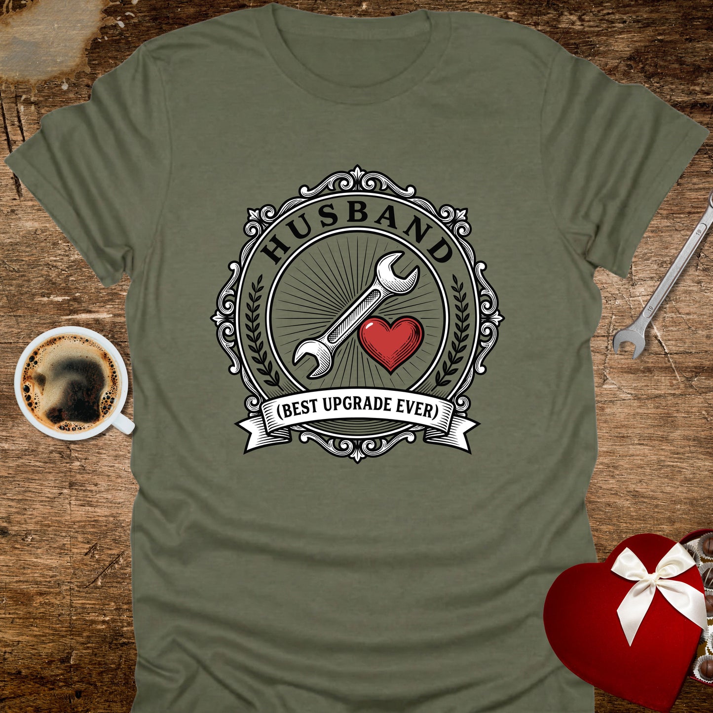 Green t-shirt with a graphic design featuring a wrench, heart, and text on a wooden surface with coffee and tools.