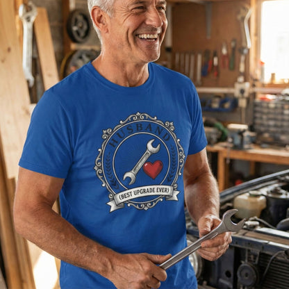 Man in a blue t-shirt with a tool graphic, holding a wrench in a workshop.