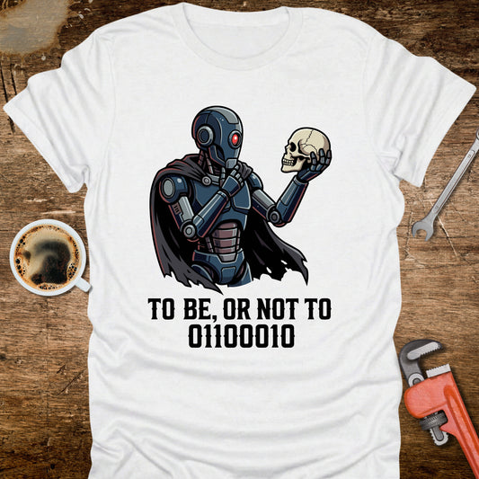 White t-shirt with robot and skull design on a wooden surface with tools and coffee.