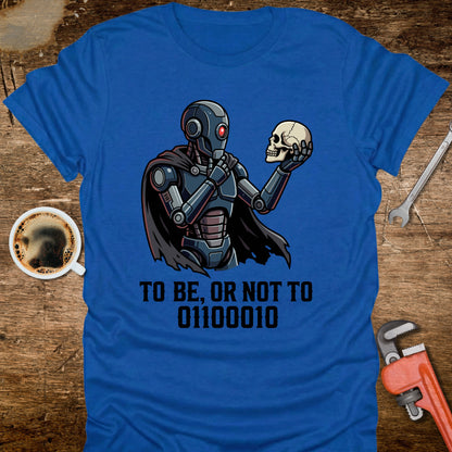 Blue t-shirt with robot holding a skull design and text on a wooden surface with tools and coffee.