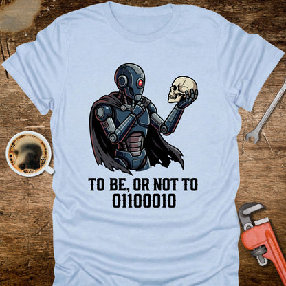 Light blue t-shirt with a robot holding a skull and text on a wooden surface with coffee and tools.
