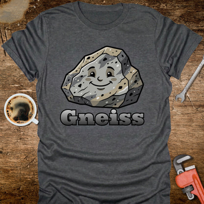 Gray t-shirt with a cartoon gneiss stone graphic and the word 'Gneiss' on a wooden surface with a coffee cup and tools.