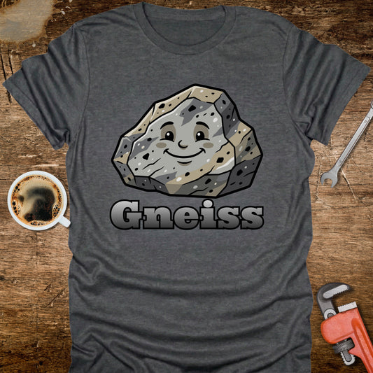 Gray t-shirt with a cartoon gneiss stone graphic and the word 'Gneiss' on a wooden surface with a coffee cup and tools.