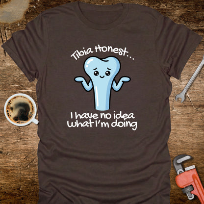 Brown t-shirt with a cartoon tooth graphic and text on a wooden surface with coffee and tools.