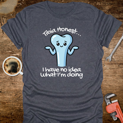 Gray t-shirt with a cartoon tooth graphic and text on a wooden surface with coffee and tools.