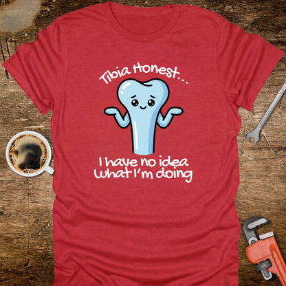 Red t-shirt with a cartoon tooth graphic and text on a wooden surface with a coffee cup and tools.