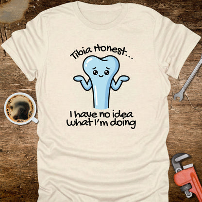 Beige t-shirt with a cartoon tooth graphic and text on a wooden surface with coffee and tools.