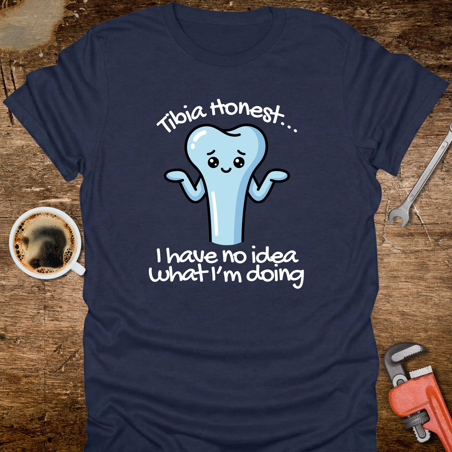 Navy blue t-shirt with a cartoon tooth graphic and text on a wooden surface with coffee and tools.