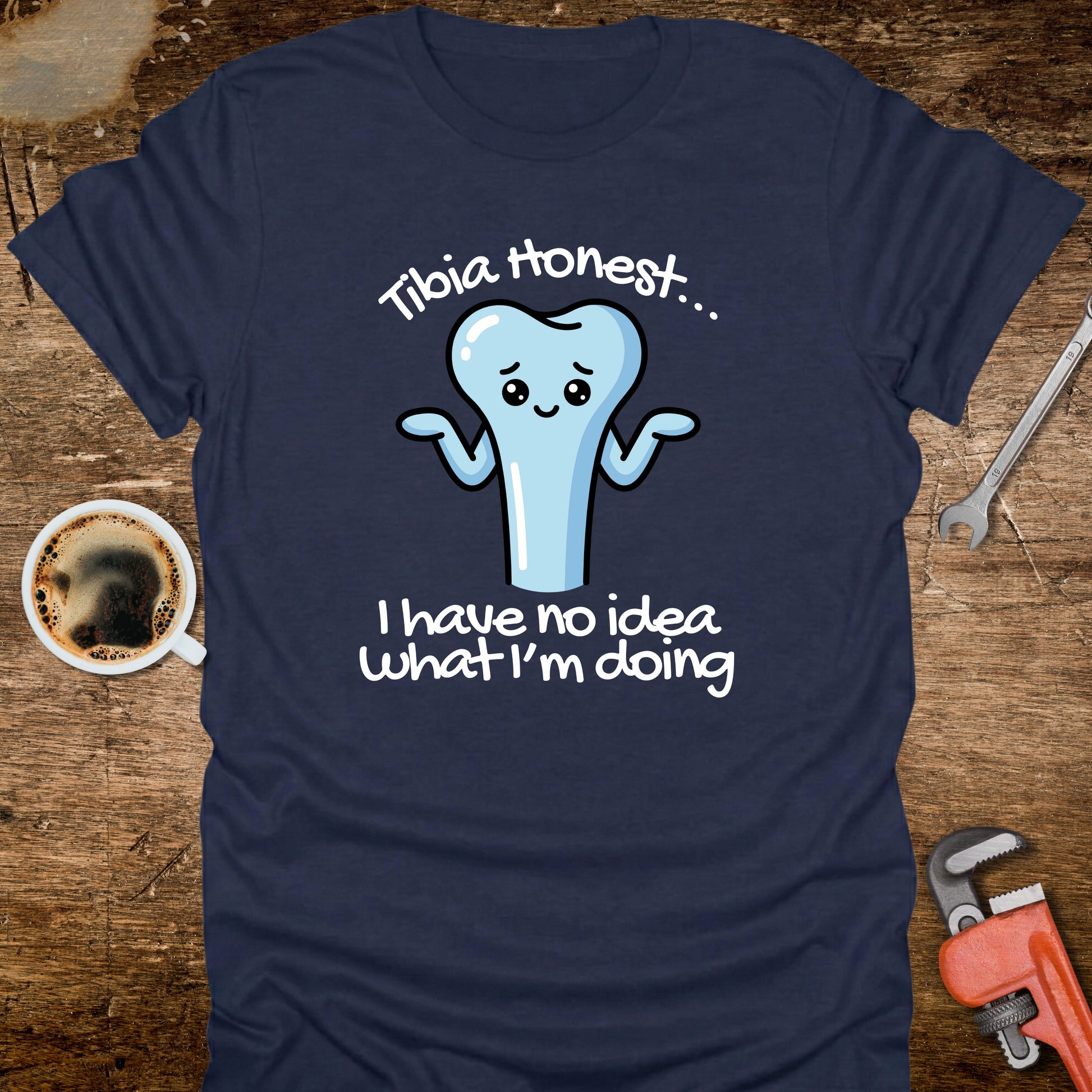 Navy blue t-shirt with a cartoon tooth graphic and text on a wooden surface with coffee and tools.